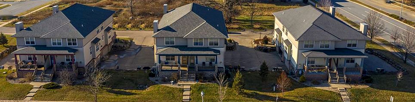 Aerial view of three Meir Property Group duplexes with front porches, lawns and shared parking