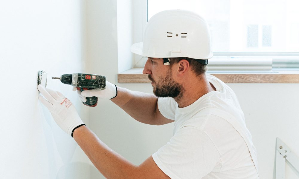 Maintenance technician using a drill to install an outlet cover